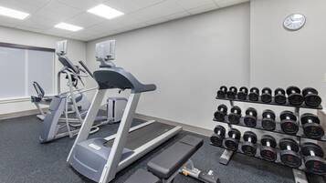 A gym with treadmills, a stair climber, and a rack of dumbbells.