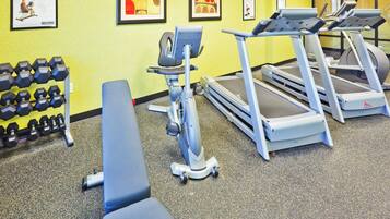 A gym with exercise equipment including treadmills, a stationary bike, and dumbbells.