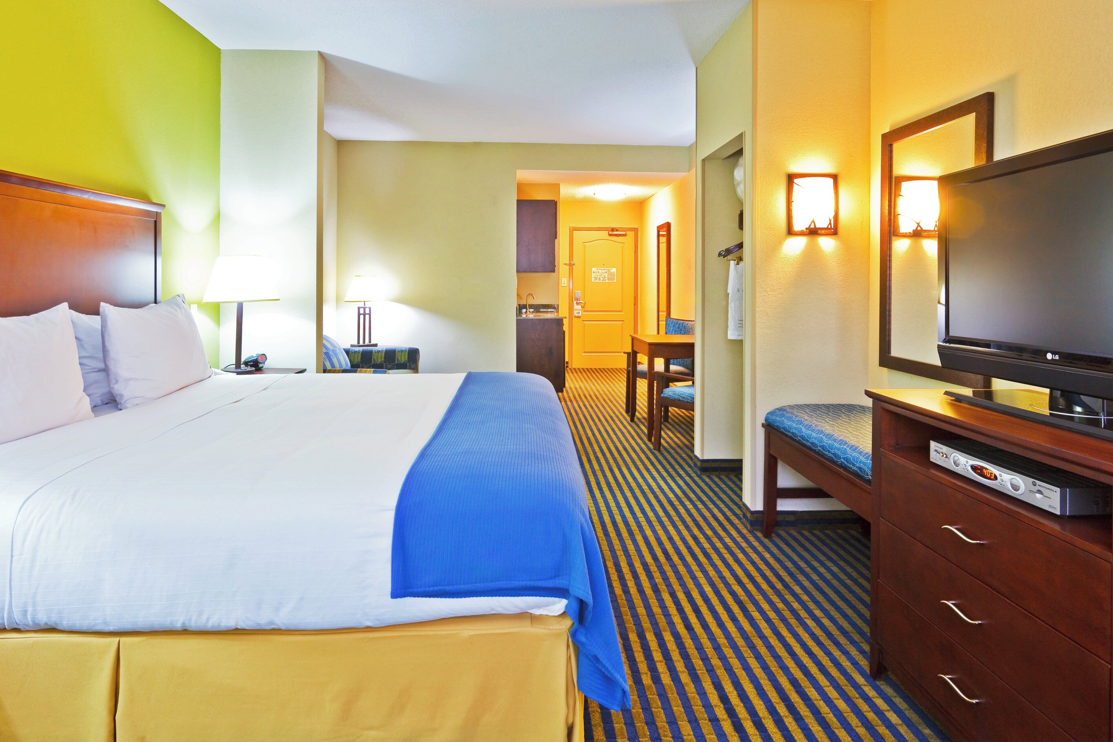 Una habitación de hotel con una cama, televisión, escritorio y silla.