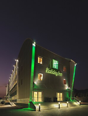 A building with a sign reading 'Holiday Inn' and a staircase leading to the entrance. - Holiday Inn Salerno - Cava De'Tirreni by IHG (Cava de' Tirreni)