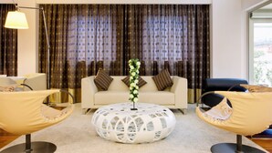 Un salon moderne comprenant un canapé, deux fauteuils, une table basse et une lampe.