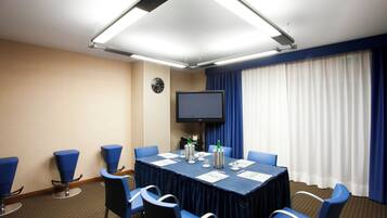 A conference room with a table, chairs, a clock, and a television.