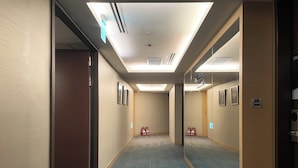 A hotel hallway with carpeted floors, framed pictures on the walls, and a door on the left. - Holiday Inn Express Taoyuan by IHG (Taoyuan City)