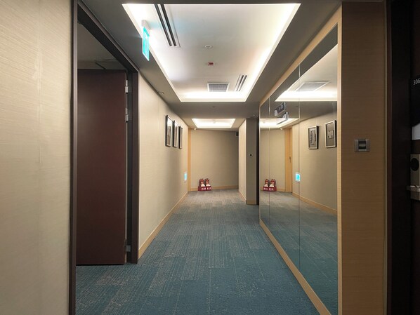 A hotel hallway with carpeted floors, framed pictures on the walls, and a door on the left. - Holiday Inn Express Taoyuan by IHG (Taoyuan City)
