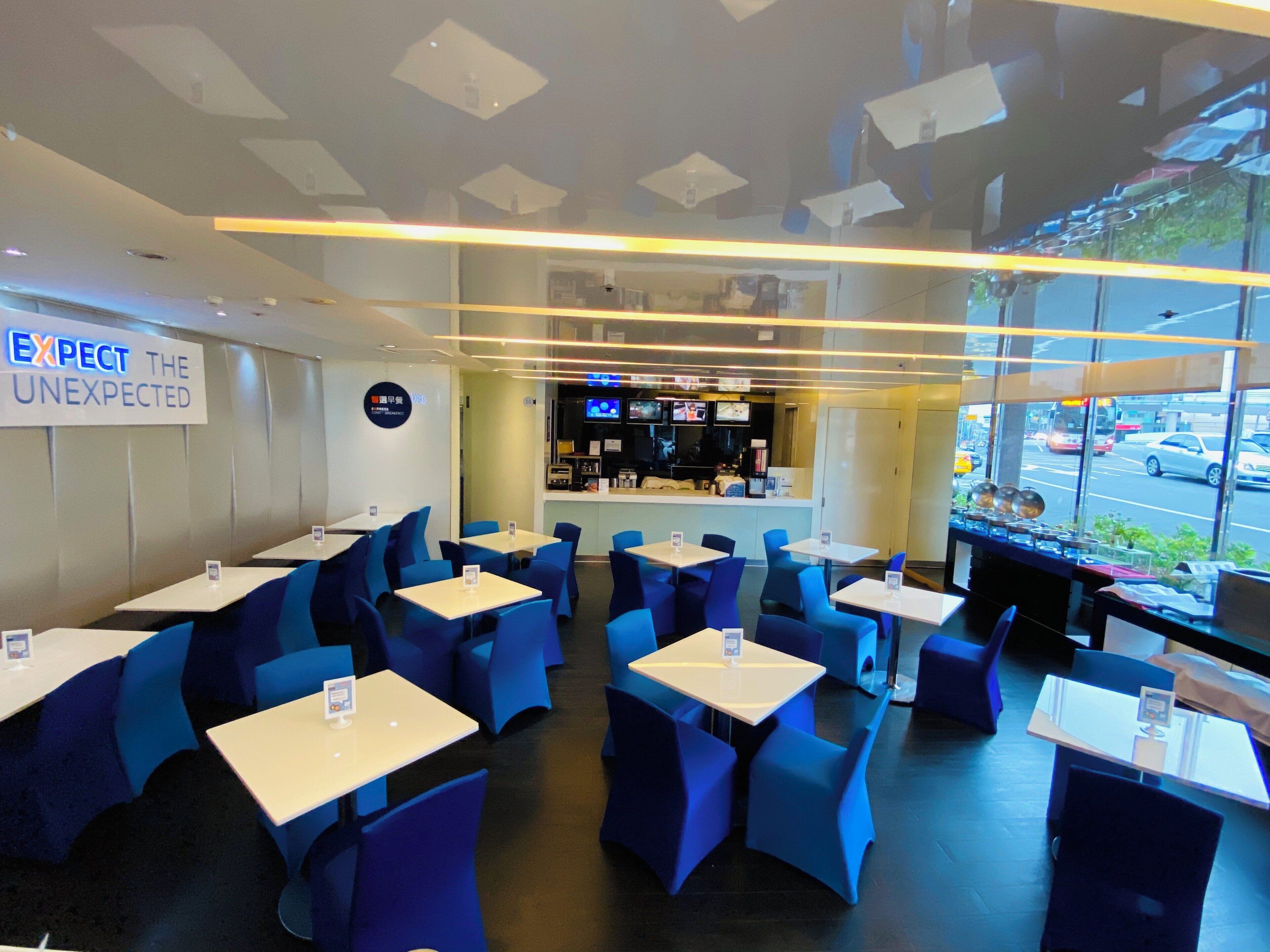 Interior de un restaurante con mesas, sillas, una barra con un menú y un letrero en la pared.