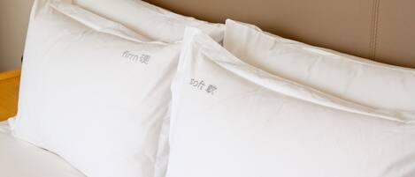 Una cama con almohadas blancas y un cabecero color beige.