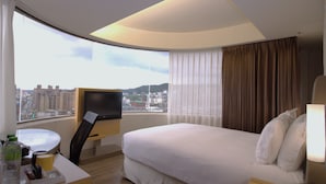 A hotel room with a bed, a desk with a TV, a window with curtains, and a city view. - Holiday Inn Express Taoyuan by IHG (Taoyuan City)