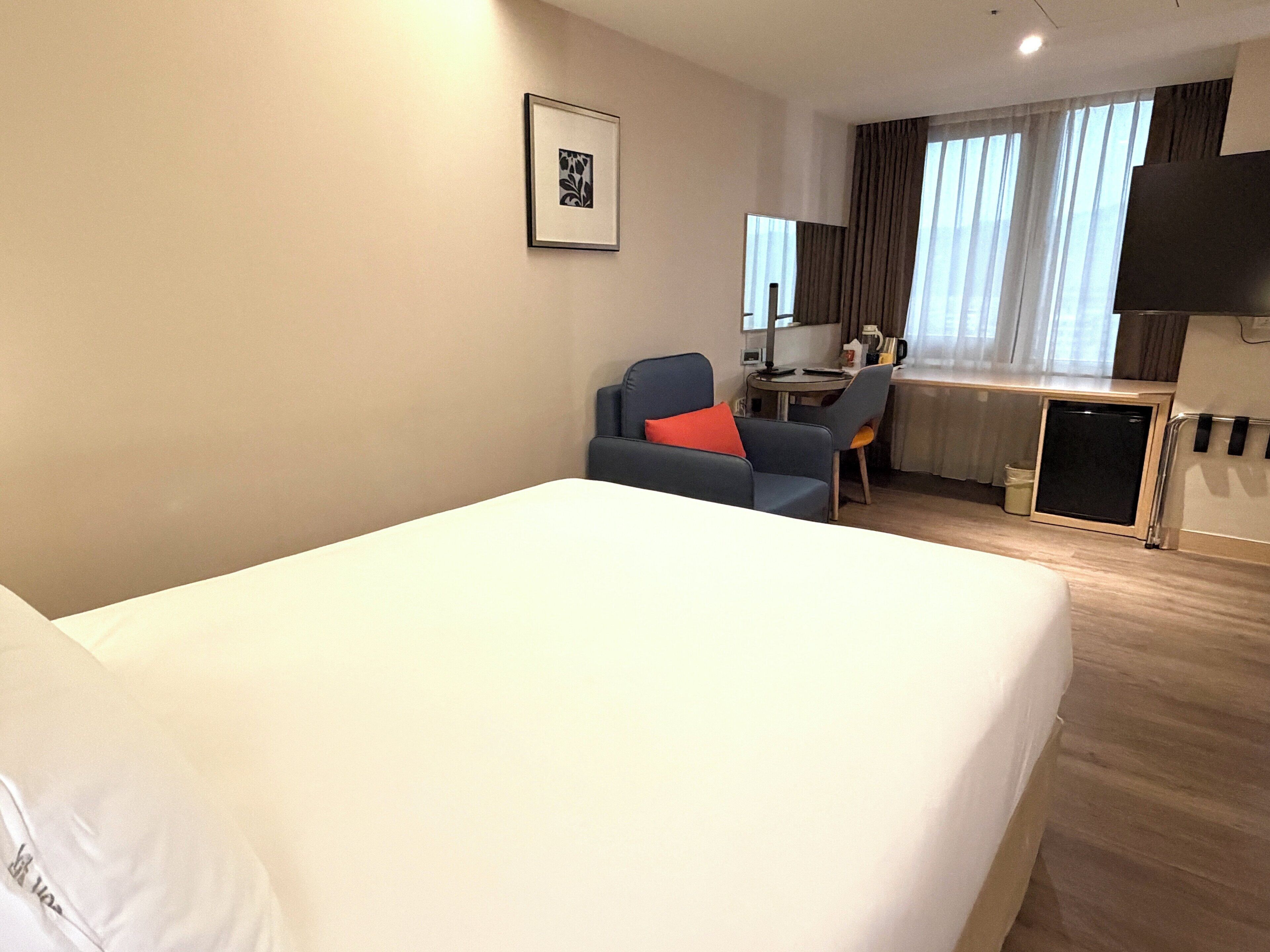 Habitación de hotel con una cama grande, un escritorio, una silla y un televisor.