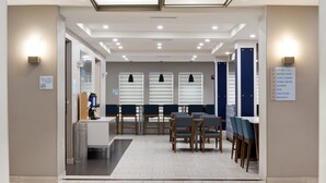A hotel lobby with a reception desk, seating area, and directional sign.