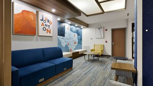 A modern waiting area with a blue sofa, a yellow chair, and a small table.