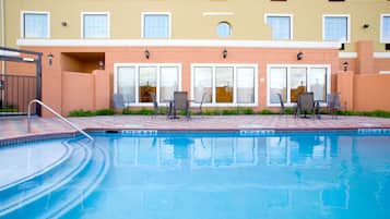 Una piscina al aire libre, sillones reclinables de piscina