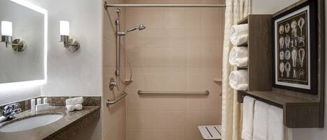 Un baño con lavabo, espejo, ducha y toallero.
