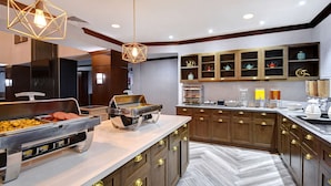 A modern kitchen with wooden cabinets, a buffet counter, and a herringbone floor pattern. - Homewood Suites by Hilton Yorktown Newport News (Yorktown)