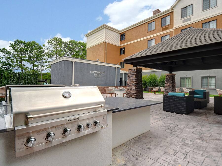 A backyard with a built-in grill, outdoor seating, and a stone pillar.