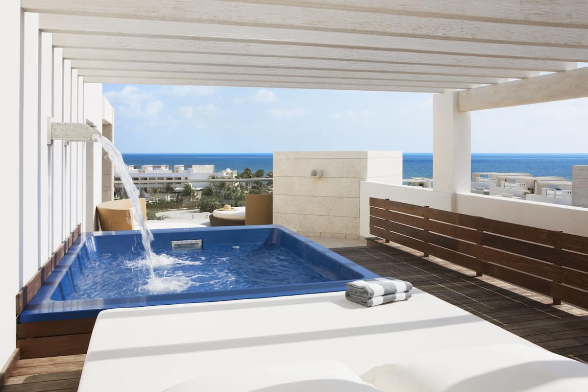 Uma banheira de hidromassagem no terraço com vista desobstruída para o oceano e a paisagem urbana.