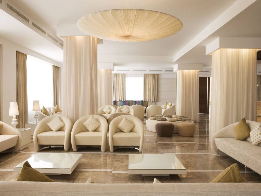 A spacious living room with a large chandelier, multiple sofas, and a coffee table.