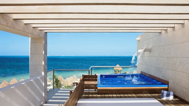 Eine Holzterrasse mit Whirlpool und Blick auf den Ozean.