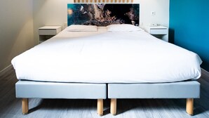 Un dormitorio moderno con una cama grande, listones de madera sobre la cabecera, dos mesitas de noche y una lámpara fijada a la pared.