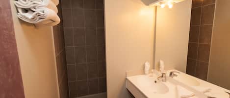 Un baño moderno con lavamanos doble, un espejo grande y un perchero para toallas.