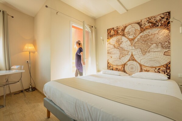 Un dormitorio con una cama grande, un escritorio con una lámpara y un mural de un mapa en la pared.