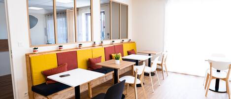 A modern cafe with wooden tables and benches, large windows, and a bright interior.