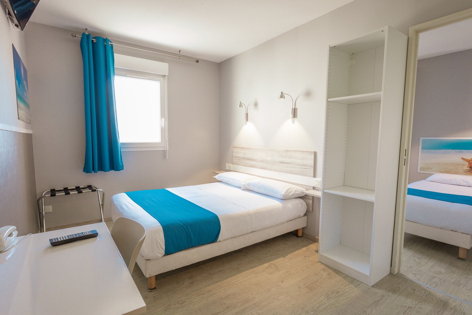 Un dormitorio con cama, escritorio, silla, ventana con cortinas y armario.