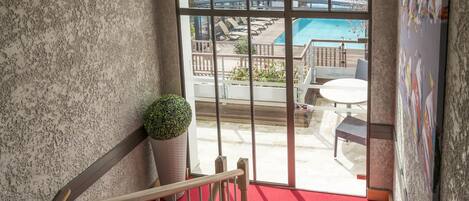 Una escalera con alfombra roja que lleva a un balcón con vista a una piscina.