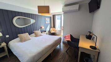 Ein Hotelzimmer mit einem großen Bett, einem Schreibtisch, einem Sessel, einer Lampe und einem Fernseher.