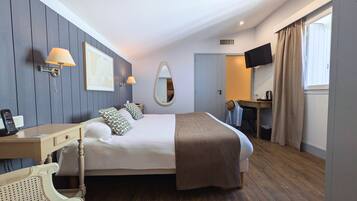 Una habitación de hotel con una cama grande, lámparas de noche, un escritorio, una silla, un espejo y un televisor.