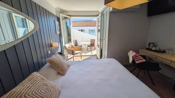 Een hotelkamer met een bed, een bureau, een stoel, een tafel en een balkon met stoelen en een tafel.