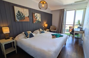A hotel room with a large bed, two bedside tables, a desk, and a chair. There are two wall-mounted lamps and a ceiling light. - Logis Hôtel de la Marée - Ile de Ré (Rivedoux-Plage)