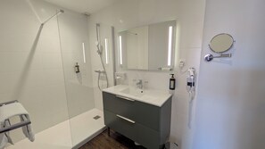 A modern bathroom with a walk-in shower, a sink with a mirror, and a towel rack. - Logis H ôtel de la Marée - Ile de Ré (Rivedoux-Plage)
