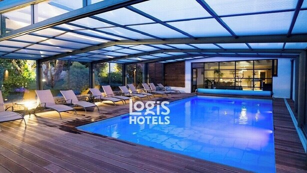 A swimming pool area with lounge chairs and a glass-enclosed structure. - Logis Hôtel de la Marée - Ile de Ré (Rivedoux-Plage)