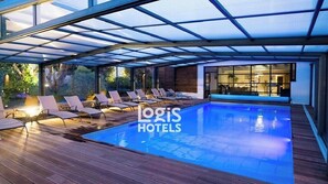 A swimming pool area with lounge chairs and a glass-enclosed structure. - Logis Hôtel de la Marée - Ile de Ré (Rivedoux-Plage)