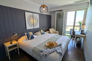 Une chambre d’hôtel équipée d’un lit, d’un bureau, d’une chaise, d’une table de chevet et d’une grande fenêtre donnant sur un beau paysage.