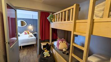 A room with a bunk bed, a desk, a chair, a bed, a mirror, and a window with curtains.