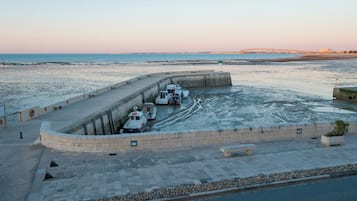 Un paseo marítimo con barcos amarrados, un puente al fondo y cielo despejado.