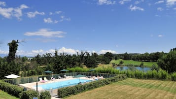 Een buitenzwembad, ligstoelen bij het zwembad