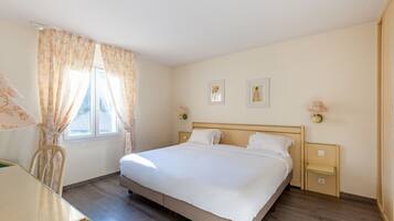 Une chambre à coucher avec un lit, une chaise, une table et une fenêtre avec des rideaux.