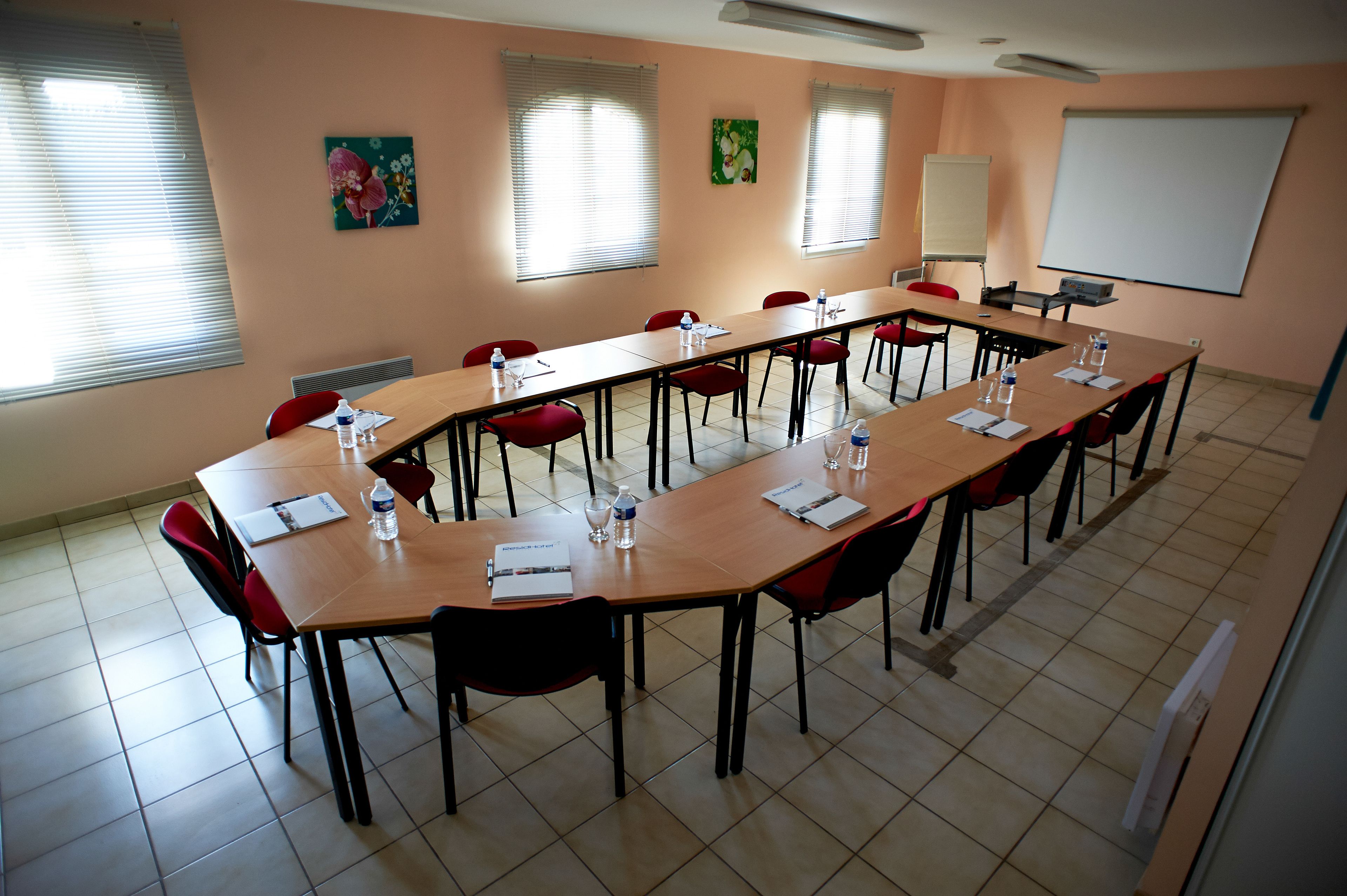 A conference room with a long table, red chairs, and a whiteboard.