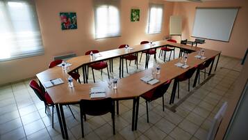 A conference room with a long table, red chairs, and a whiteboard.