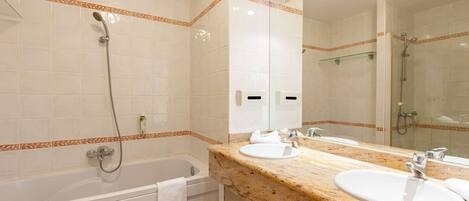 Une salle de bain avec une baignoire, deux lavabos, un grand miroir et un espace douche.