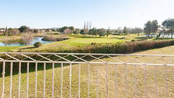 Un campo de golf con un estanque, árboles y cielo despejado.