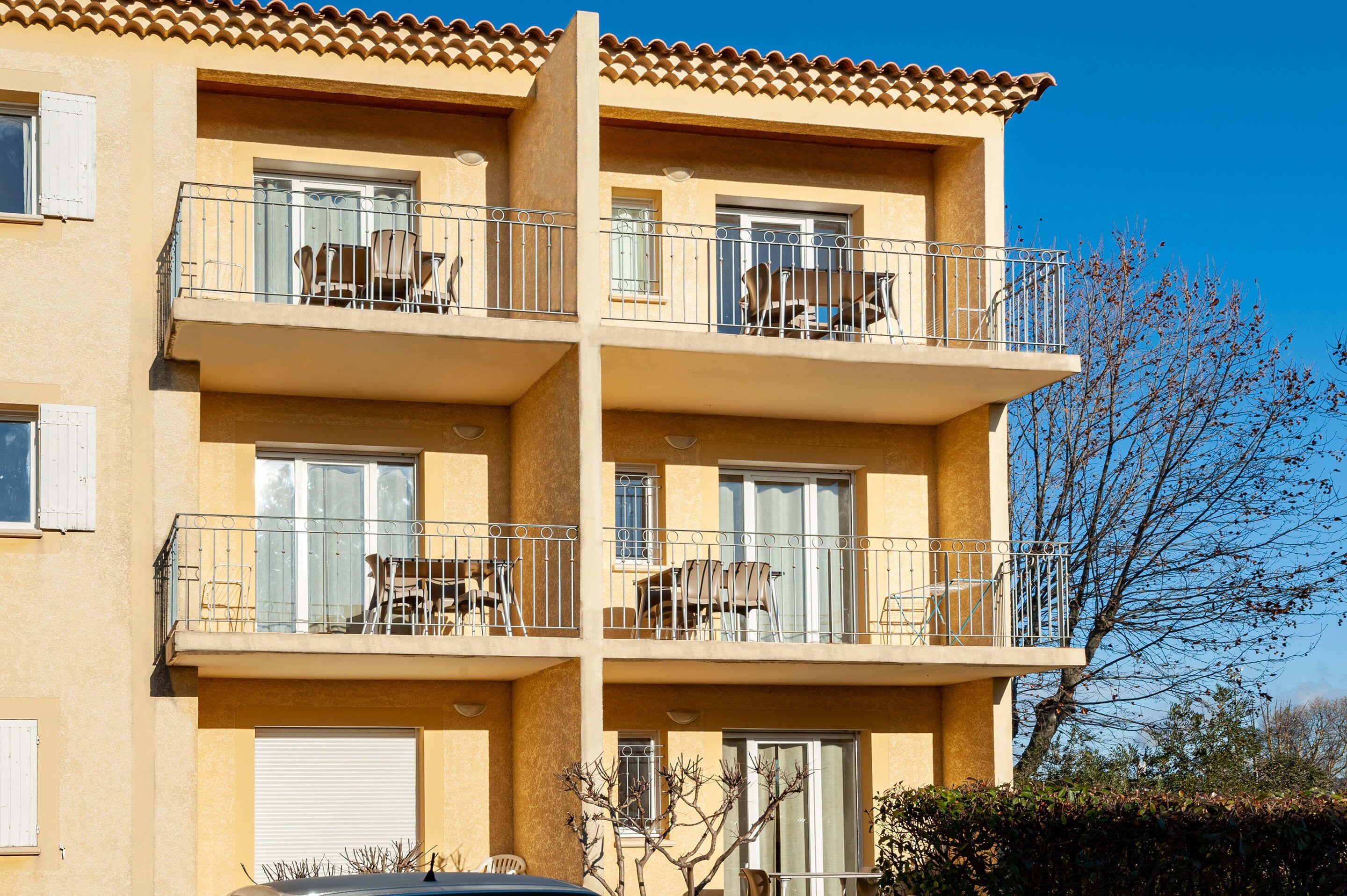 Un edificio de varios pisos con balcones, cada uno con mobiliario exterior.