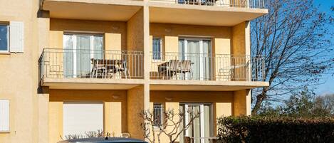 A multi-story building with balconies, each equipped with outdoor furniture.
