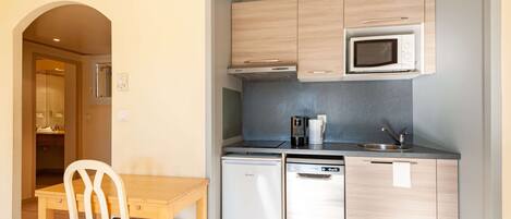 Eine kompakte Küche mit Mikrowelle, Kaffeemaschine und Geschirrspüler.