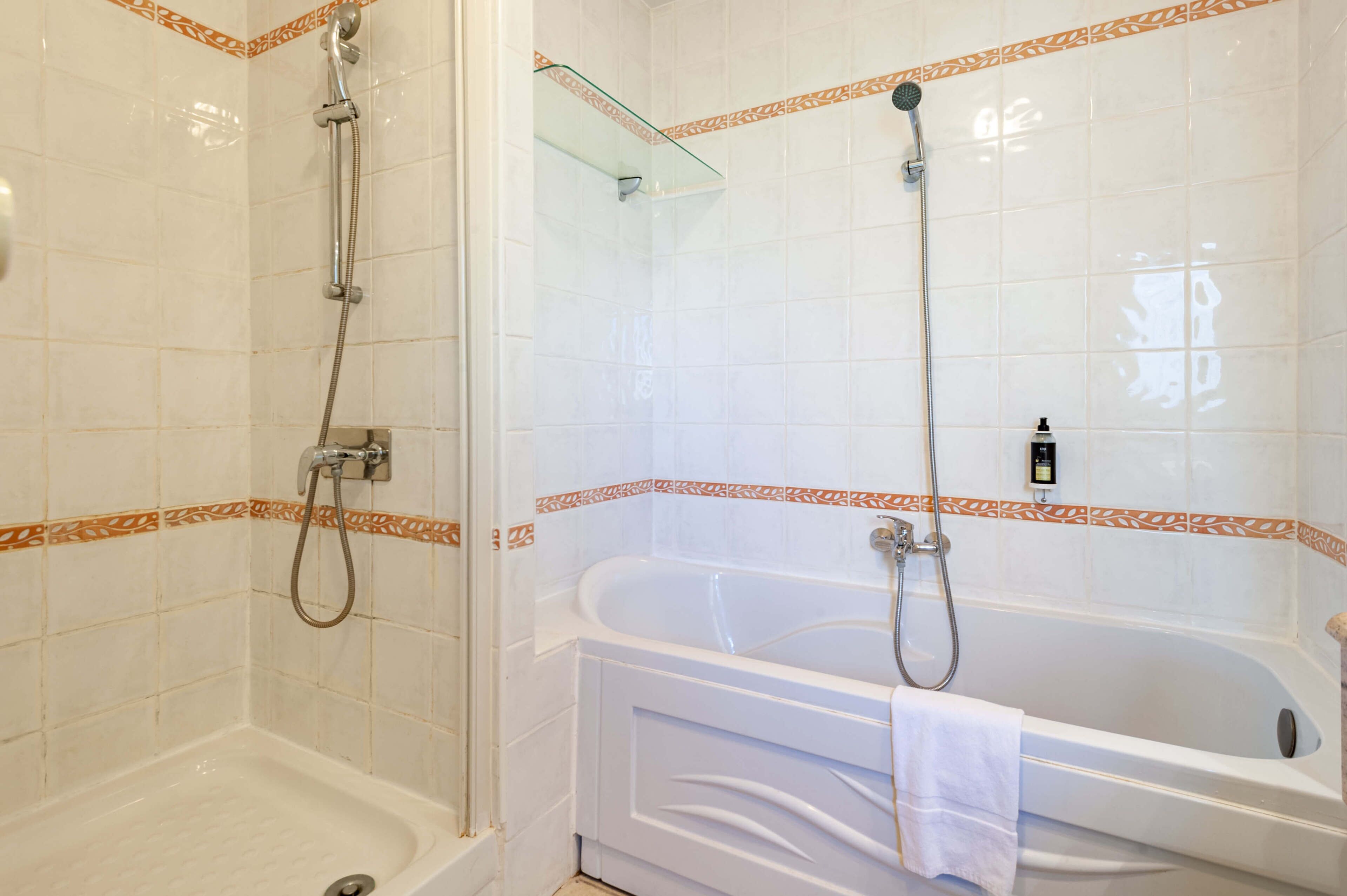 Un baño con ducha, bañera y cabina de ducha con paredes de vidrio.