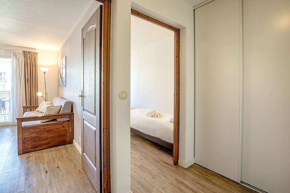 Habitación de hotel con cama de madera, sofá, lámpara y vistas al exterior.
