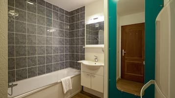 A bathroom with a bathtub, a sink, and a mirror.
