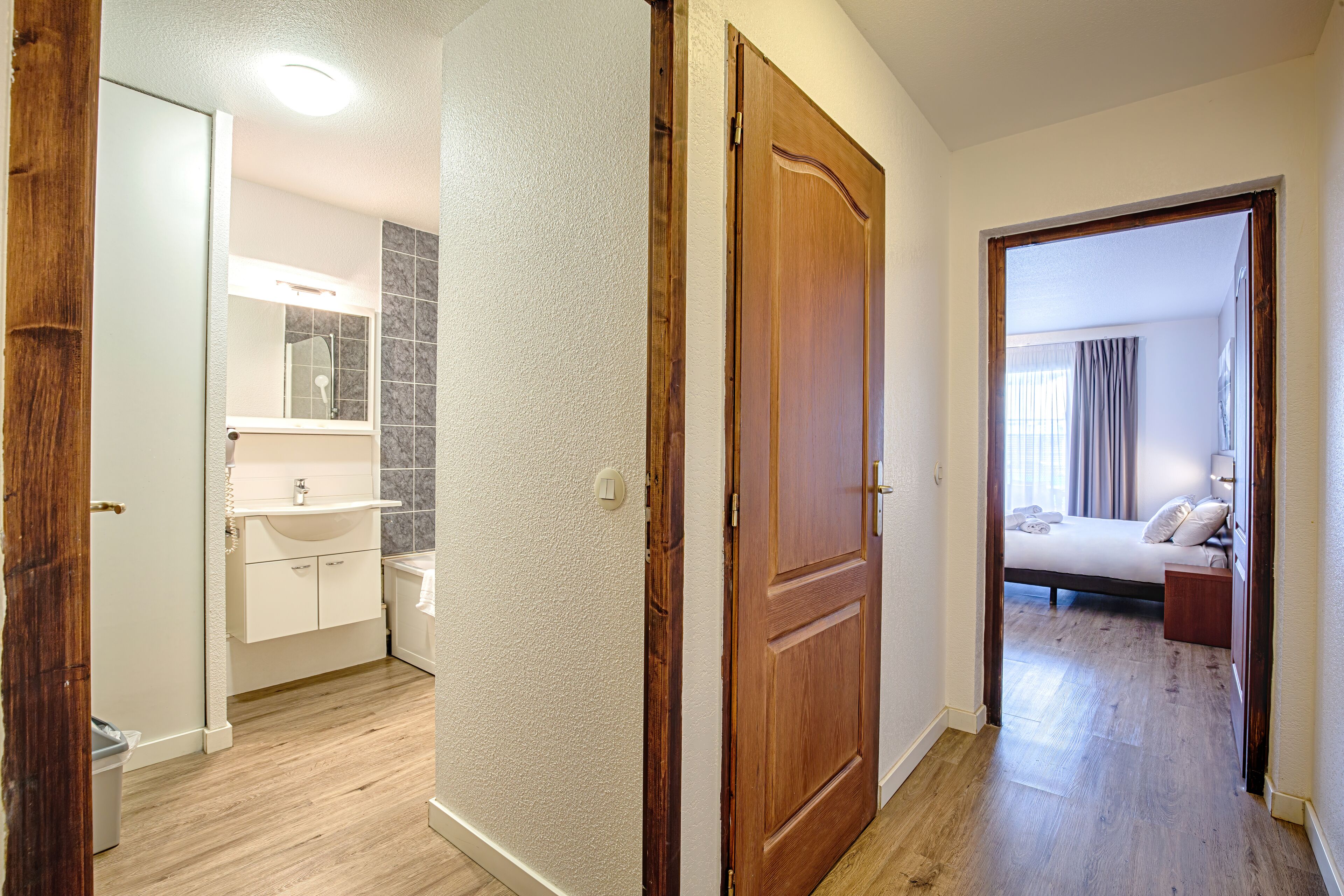 Een slaapkamer met een houten deur, een bed en een raam met gordijnen.